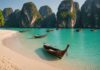 Voyage en Thaïlande : le guide pratique pour bien préparer son séjour Plage tropicale en Thaïlande avec bateaux longue-queue et falaises calcaires au coucher du soleil